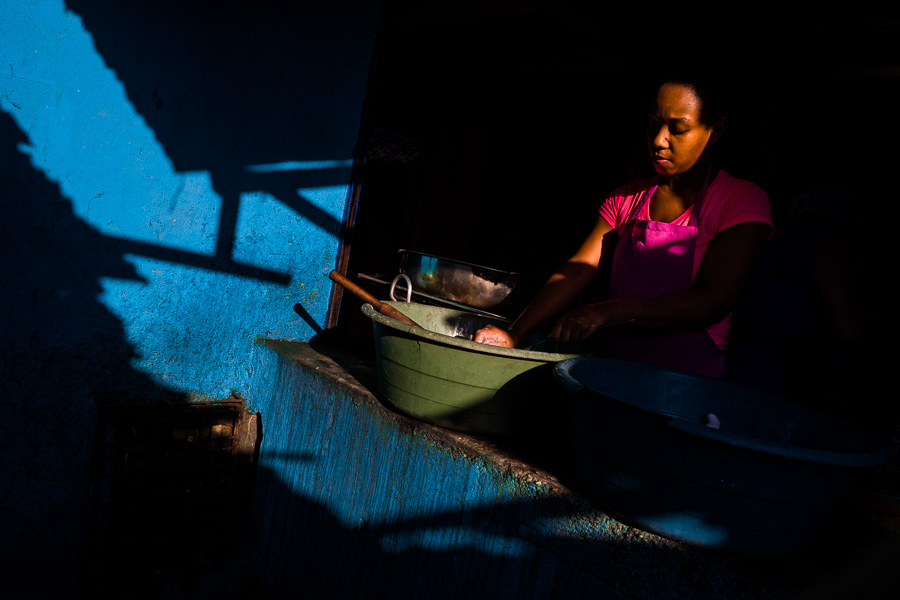 A young Afro-Colombian woman washes the dishes in a street restaurant in Cartagena, Colombia.
