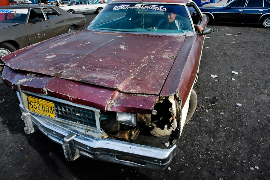 A rusty and damaged American classic car from 1970s used as a shared taxi