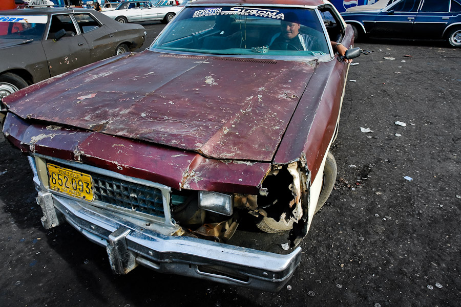 A rusty and damaged American classic car from 1970s used as a shared taxi 