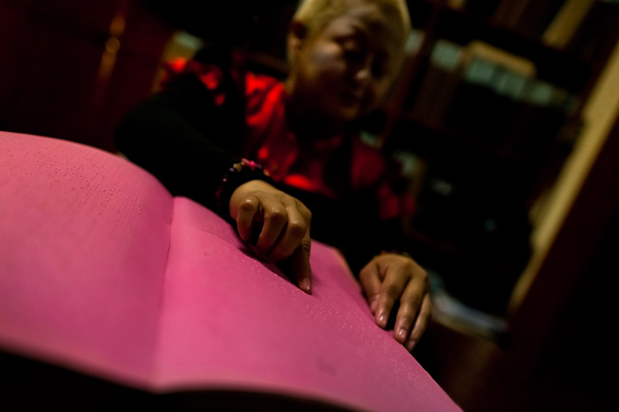 A blind girl reads a book written in Braille at Unión Nacional de Ciegos del Perú, a social club for the visually impaired in Lima, Peru.