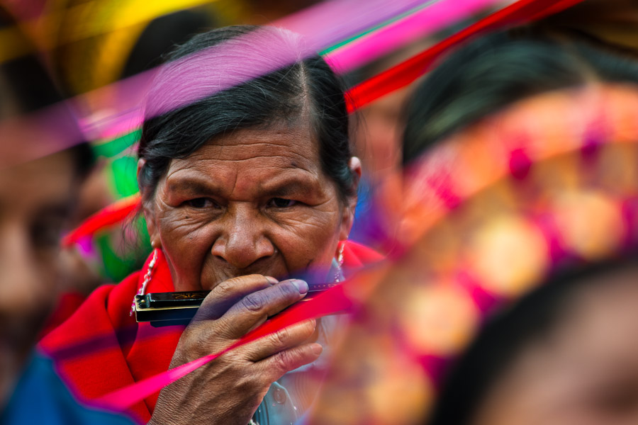 A native woman from the Kamentsá tribe, wearing a colorful costume, plays harmonica during the Carnival of Forgiveness, a traditional indigenous celebration in Sibundoy, Colombia.