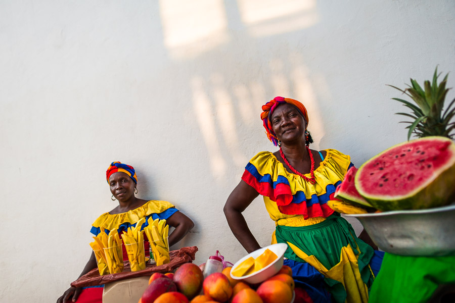 Afro-Colombian women, dressed in the traditional ‘palenquera’ costume, sell fruits on the street of Cartagena, Colombia.