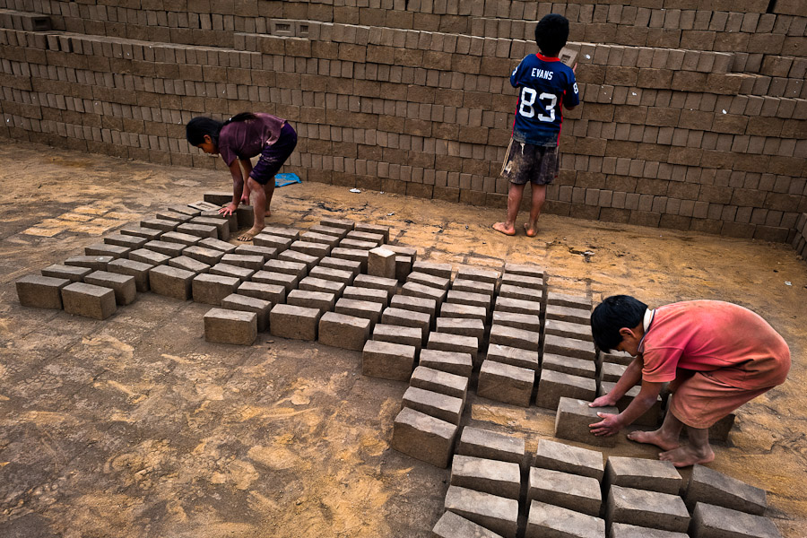 Peruvian children collect raw bricks for burning at a brick factory in Huachipa, a suburb in the outskirts of Lima, Peru.
