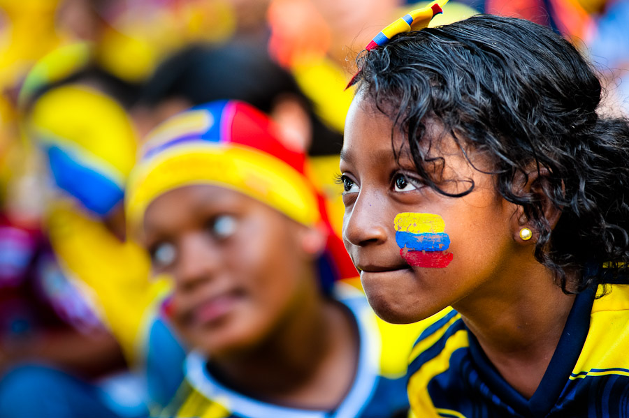 A Colombian girl, with the national flag painted on her face, watches the football match between Colombia and Uruguay at the FIFA World Cup 2014, in a park in Cali, Colombia.