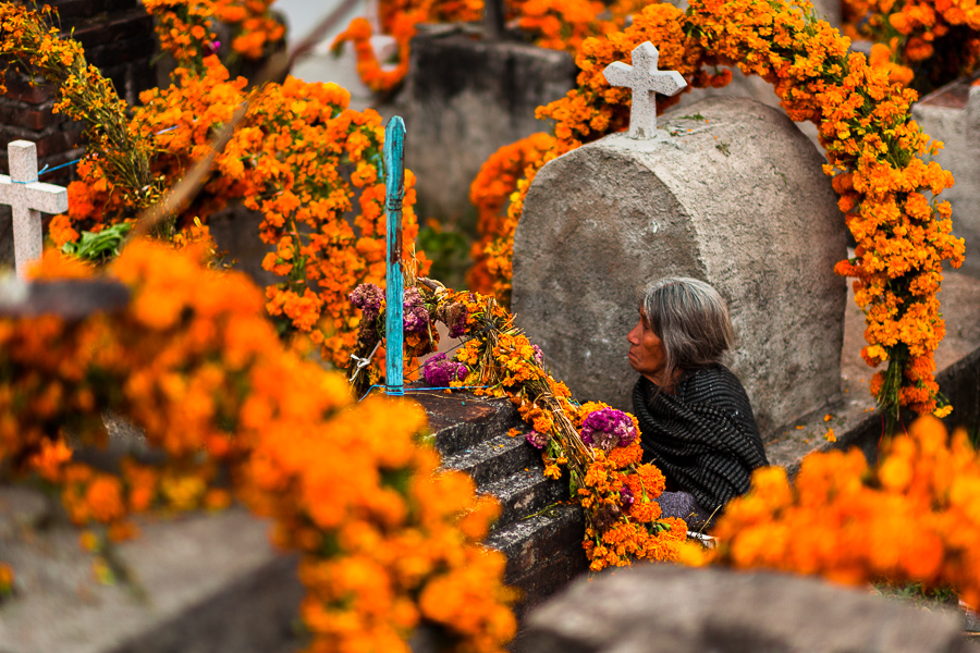 A Mixtec indigenous woman sits amongst the flower-decorated graves at a cemetery during the Day of the Dead celebrations in Metlatónoc, Guerrero, Mexico.