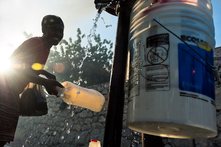 A Haitian woman fills a plastic barrel with safe drinking water from a public water pump in Port-au-Prince, Haiti.