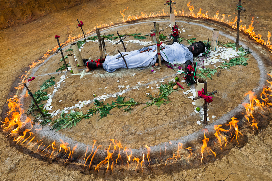 Diana R., who claims to be possessed by spirits, lies in a ring of fire during a ritual of exorcism performed by Hermes Cifuentes in La Cumbre, Colombia.