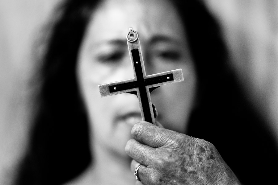 A face of a Colombian woman is seen behind the crucifix during the exorcism ritual performed at a church in Bogota, Colombia.