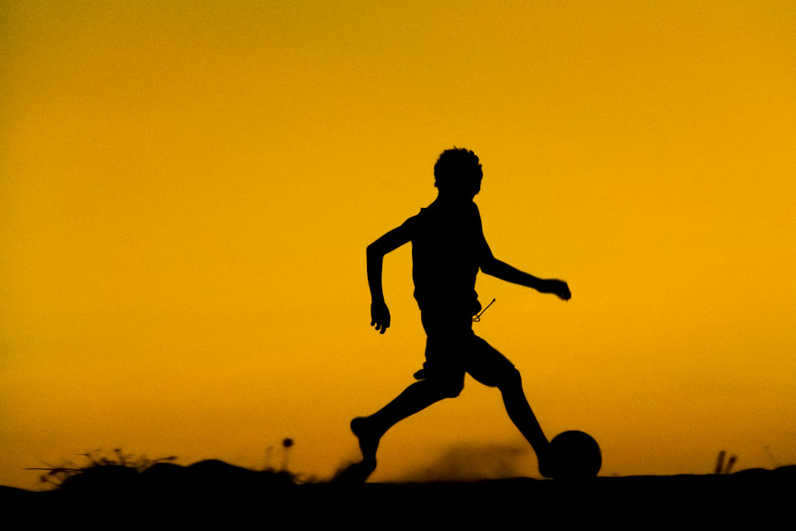 A young boy playing football on the beach in Uruau (Brazil).