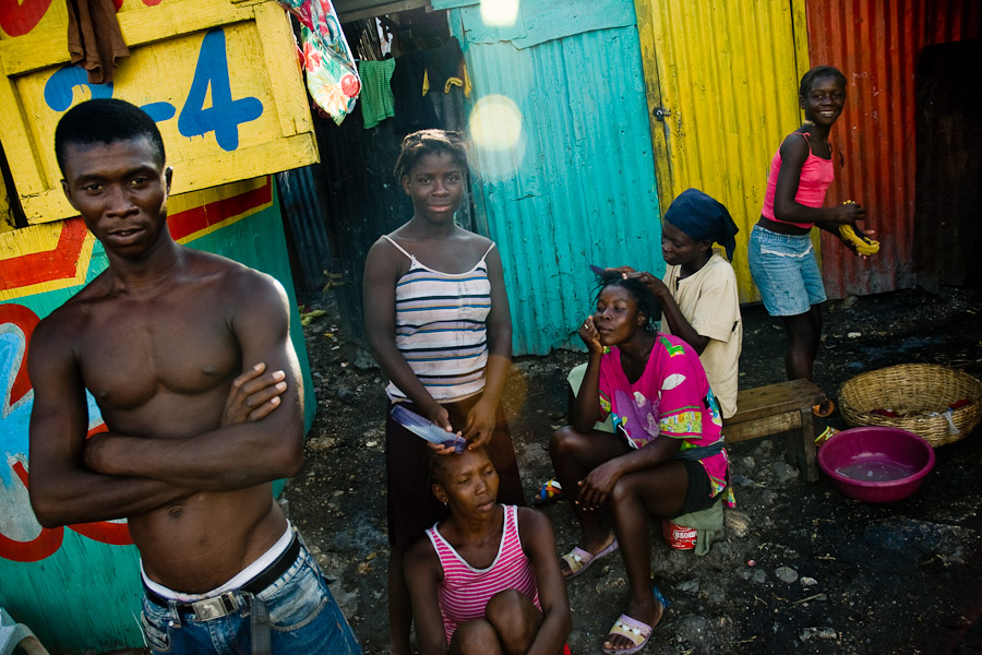 Young Haitian girls styling their hair right on the street of the La Saline slum in Port-au-Prince, Haiti.