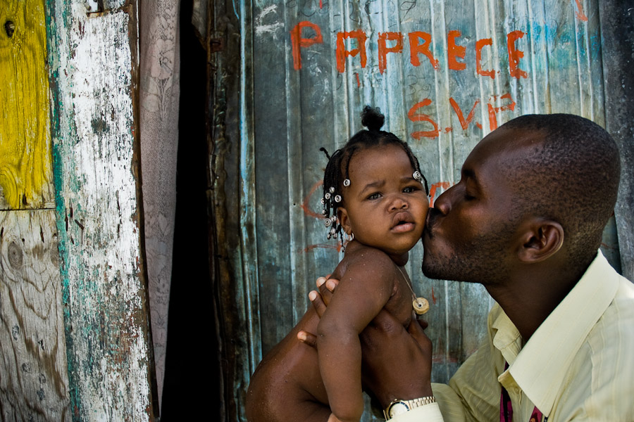 Haitian community leader kisses a baby girl in the slum of Cité Soleil, Port-au-Prince, Haiti.