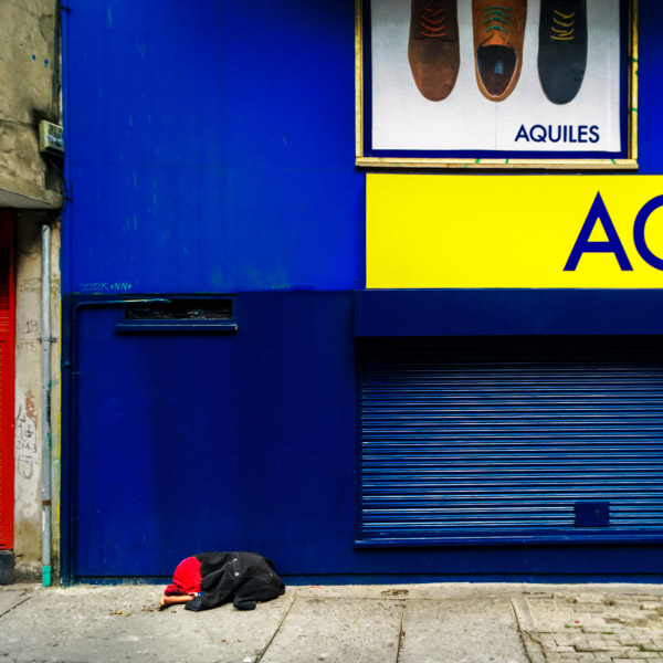 A Colombian handicapped homeless man, covered by a coat, sleeps on the street in the center of Bogotá, Colombia.