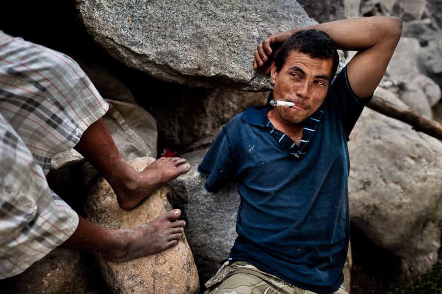 A young Honduran immigrant, having his arm amputated by a train during his previous attempt to get illegally to the United States, smokes marijuana on the bank of Suchiate river on the Guatemala-Mexico border.