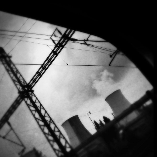 Smoking cooling towers of the Prunéřov I coal-fired power plant seen from the train passing through the industrial area in the north of the Czech Republic.