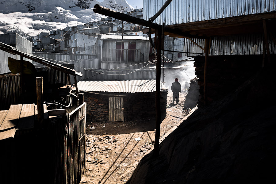 A miner walks along the corrugated metal shacks, homes of the gold miners, in La Rinconada, Peru.