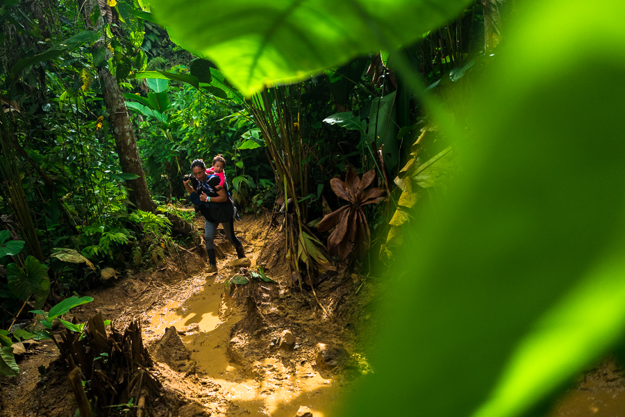 An Ecuadorian migrant, carrying her baby on her back, walks through a muddy trail in the wild and dangerous jungle of the Darién Gap between Colombia and Panamá.