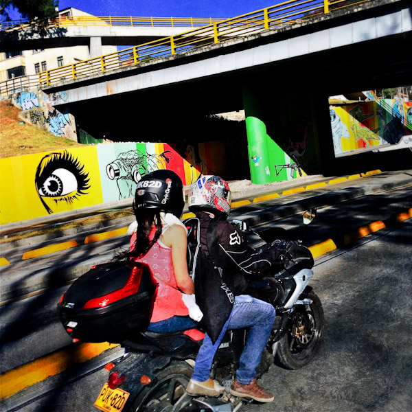 Bogotá motorcyclists drive along a large mural artwork, created on the highway retaining walls, in the center of Bogotá, Colombia.