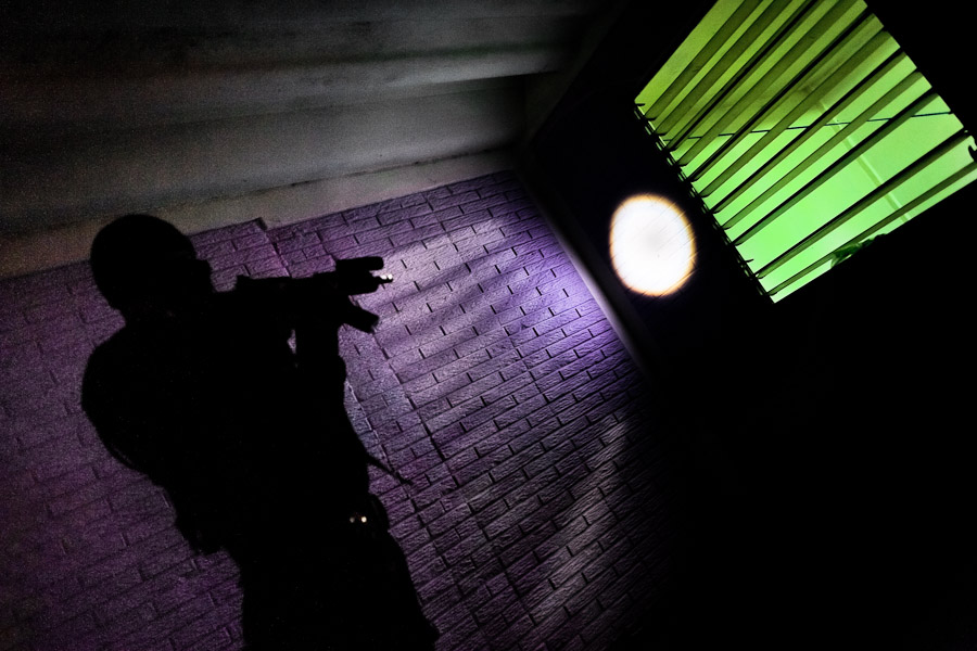 A policeman from the special anti-gang unit (Unidad Antipandillas) aims rifle at the window during a night raid in Soyapango, a gang neighborhood in San Salvador, El Salvador.