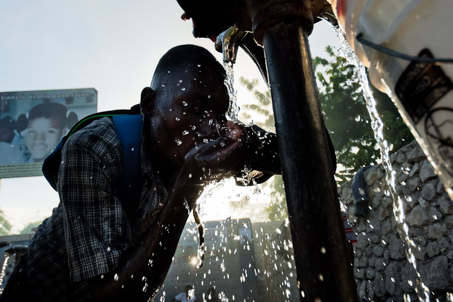 A Haitian man drinks safe water from a public water pump in Port-au-Prince, Haiti.
