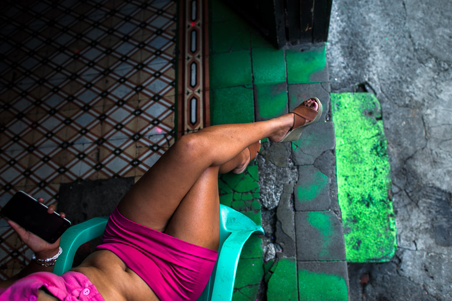 A Salvadoran sex worker chats on the phone while waiting for clients in front of a street sex bar in San Salvador, El Salvador.