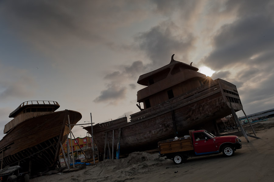 The unfinished wooden fishing vessels are seen during the sunset in an artisanal shipyard on the beach in Manta, Ecuador.