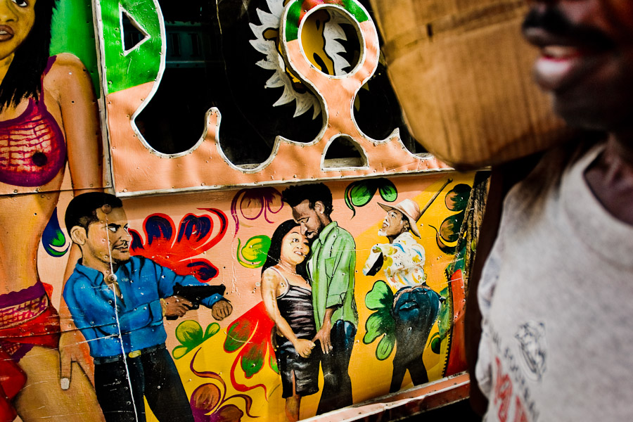 A Haitian street vendor passing the elaborately painted tap-tap bus on the street of Port-au-Prince.