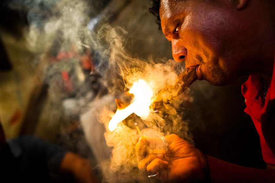 A Salvadorean ‘brujo’ (sorcerer) puffs a cigar to predict the future of his client from burn tobacco leaves in a street fortune telling shop in San Salvador, El Salvador.
