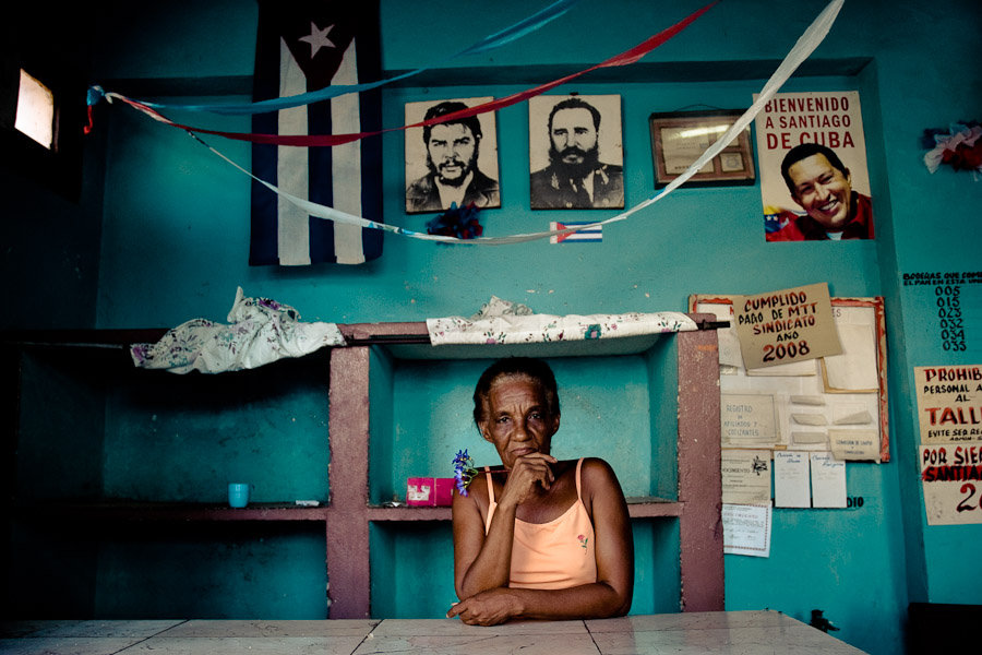 A Cuban woman stands behind the shop counter holding a flower 