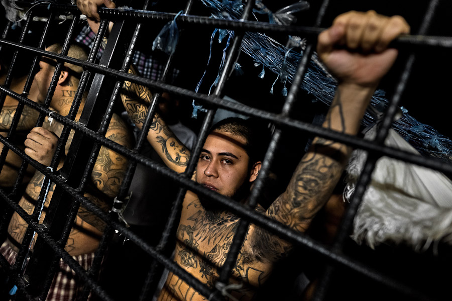 Members of the 18th Street gang (M-18) stand behind the bars in a cell at the detention center in San Salvador, El Salvador.