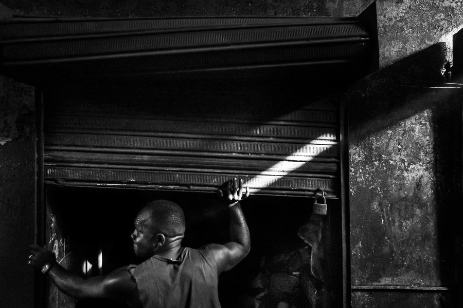An Afro-Colombian charcoal worker closes his storage room in a street market in Cartagena, Colombia.