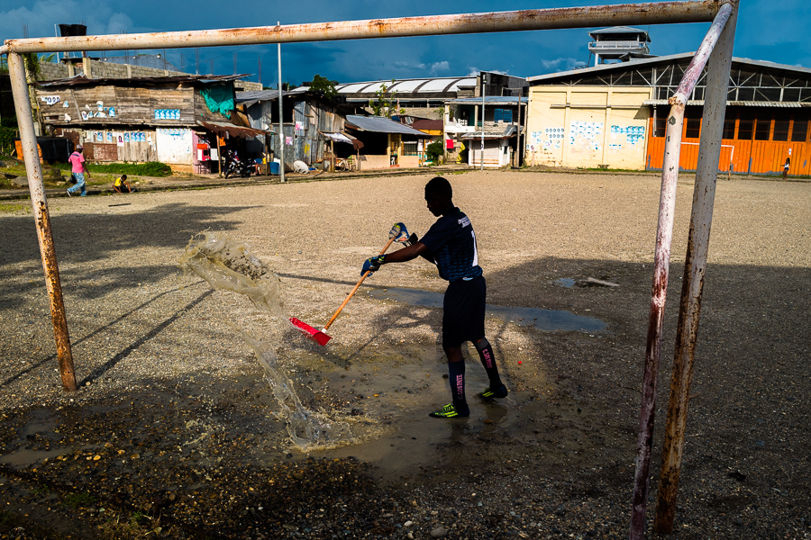 An Afro-Colombian football goal keeper removes a puddle of water before playing a match on a dirt field in Quibdó, Chocó, the Pacific department of Colombia.