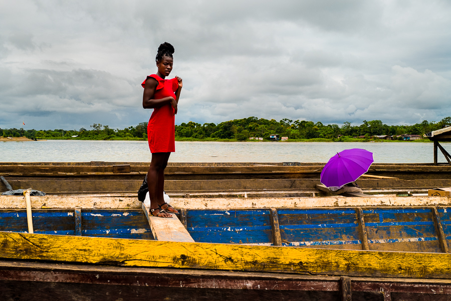 An Afro-Colombian girl stands on the top of a wooden cargo boat, anchored on the shore of the Atrato river in Chocó, Colombia.