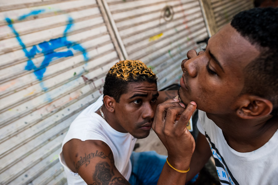 A young Colombian man shaves a friend’s beard with a razor blade in the market of Bazurto, Cartagena, Colombia.