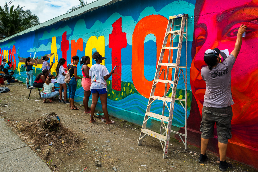 Afro-Colombian female students paint a society and environment-related mural on a school wall in Quibdó, Colombia.