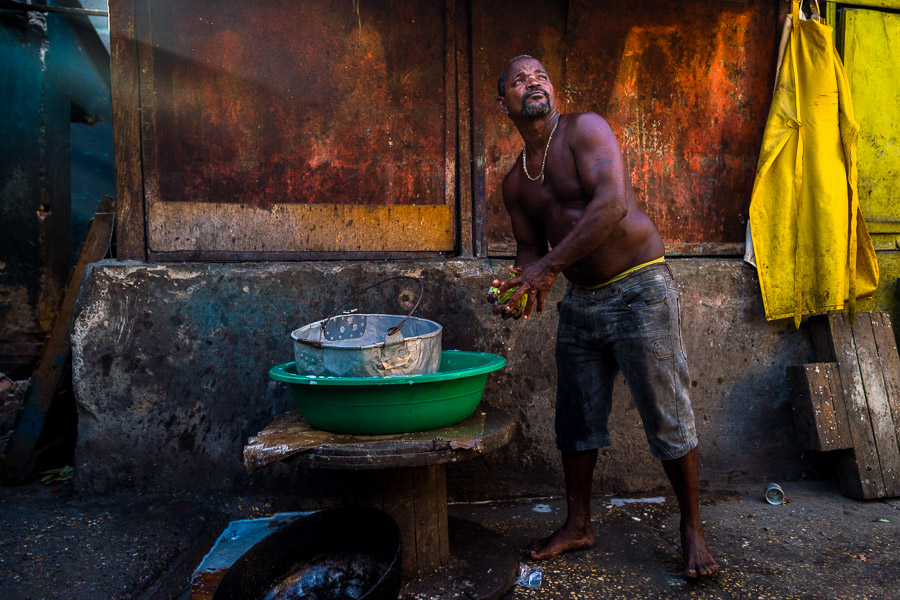 An Afro-Colombian man washes cooking pots in a street restaurant in Cartagena, Colombia.