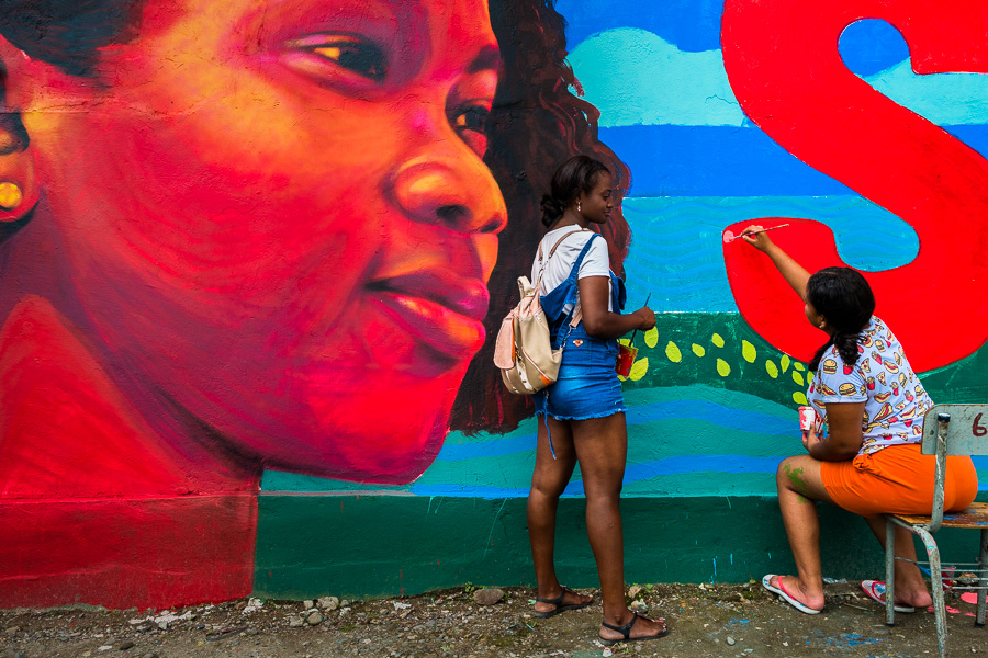 Afro-Colombian female students paint a society and environment-related mural on a school wall in Quibdó, Colombia.