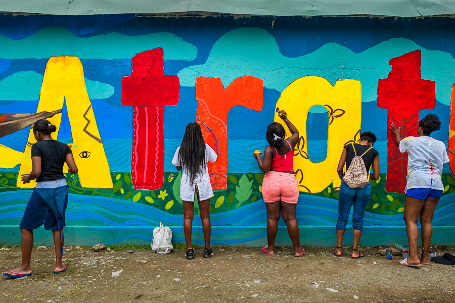 Afro-Colombian female students paint a society and environment-related mural on a school wall in Quibdó, Colombia.