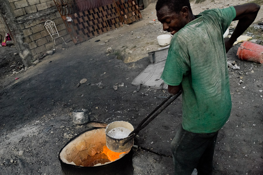 A Haitian man works with melted aluminium to make a kitchen pot in the aluminium recycling shop on the street of Port-au-Prince, Haiti.