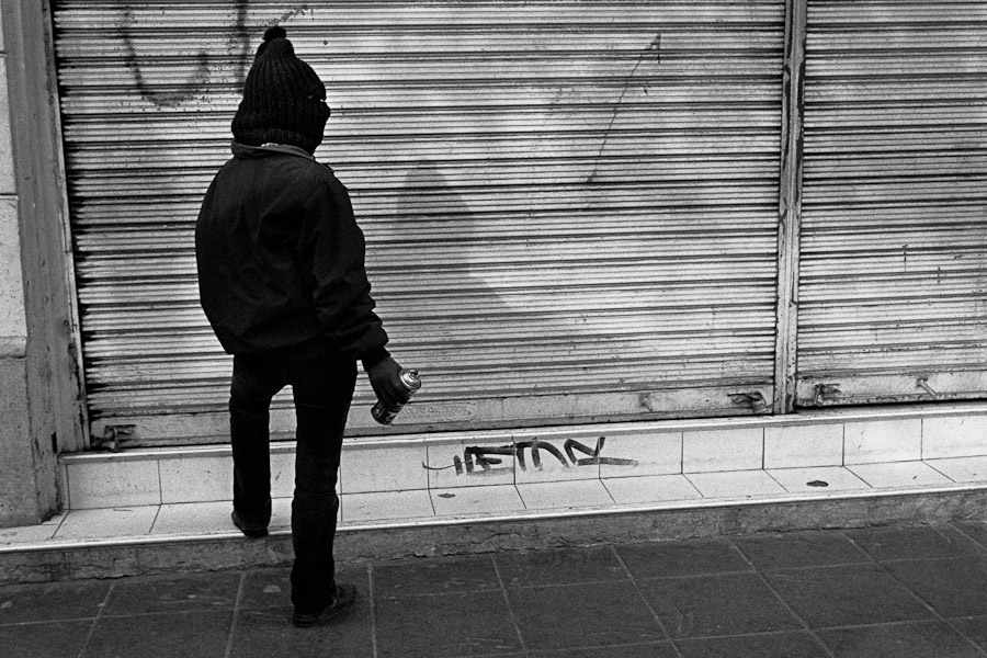 A Chilean student seen before spraying a political slogan on the roller shutter during the anti-government protest in Valparaíso, Chile.