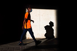 A boy with a mask walks in the street