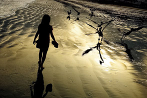 Girl walks on the beach at the sunrise