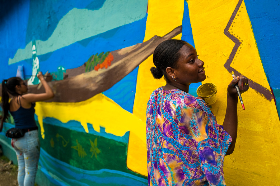 Afro-Colombian female students paint a society and environment-related mural on a school wall in Quibdó, Colombia.