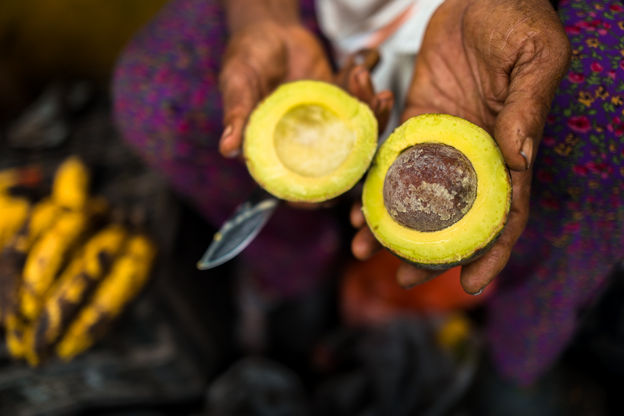 A Colombian market vendor shows a fresh, halved avocado “criollo” for sale in the street market in Cali, Colombia.