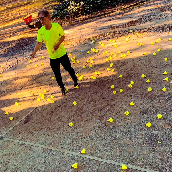 A Brazilian-Korean badminton coach performs specific racket strokes on an improvised court early in the morning in Jardim da Luz Park, São Paulo, Brazil.