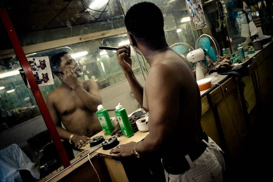 A young Cuban hairdresser shaves himself with a razor in a barber shop in Havana, Cuba.