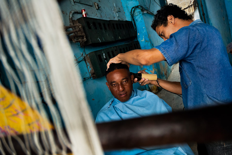 A Cuban hairdresser cuts a man's hair in an improvised barber shop in a passage of the house in Havana, Cuba.