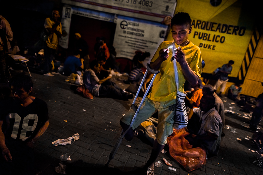 A young colombian man smokes “bazuco” (a raw cocaine paste) during the night in the street of Medellín, Colombia.