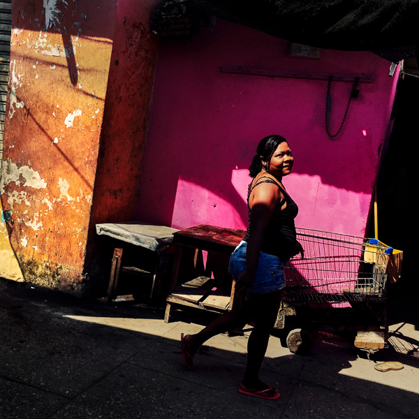 A Colombian woman walks along a customized supermarket cart parked at the market of Bazurto in Cartagena, Colombia.