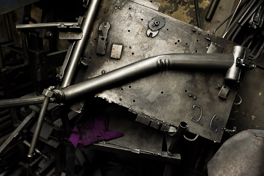 Bicycle frame tubes are seen mounted on a metal plate, fixed in a bench vice, in a small scale bicycle factory in Bogota, Colombia.