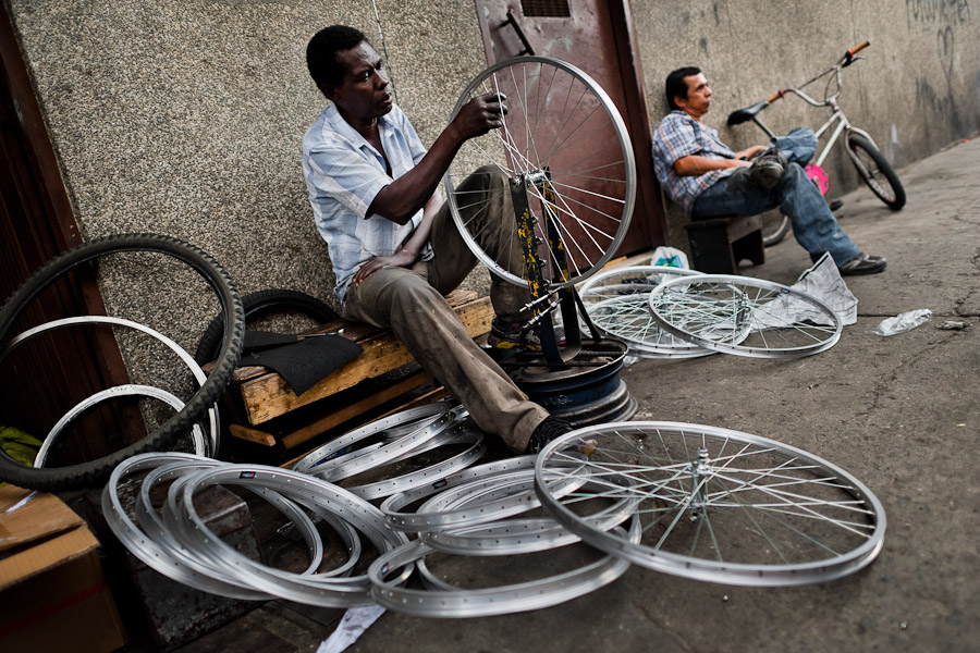 A bicycle mechanic works with a spoke wrench on bicycle wheel outside a small scale bicycle factory in Cali, Colombia.